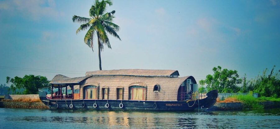 Picturesque view of river with green palms on bank and shabby wooden boathouse under blue sky in tropical countryside